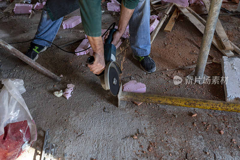 建筑工人正用金属磨床在建筑工地工作
