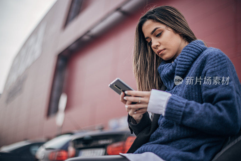 一名年轻女子在停车场上用智能手机