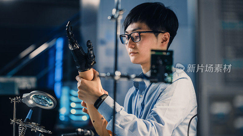 未来的假肢机器人手臂正在测试由专业的日本开发工程师在高科技研究实验室与现代计算机设备。他对结果很满意。