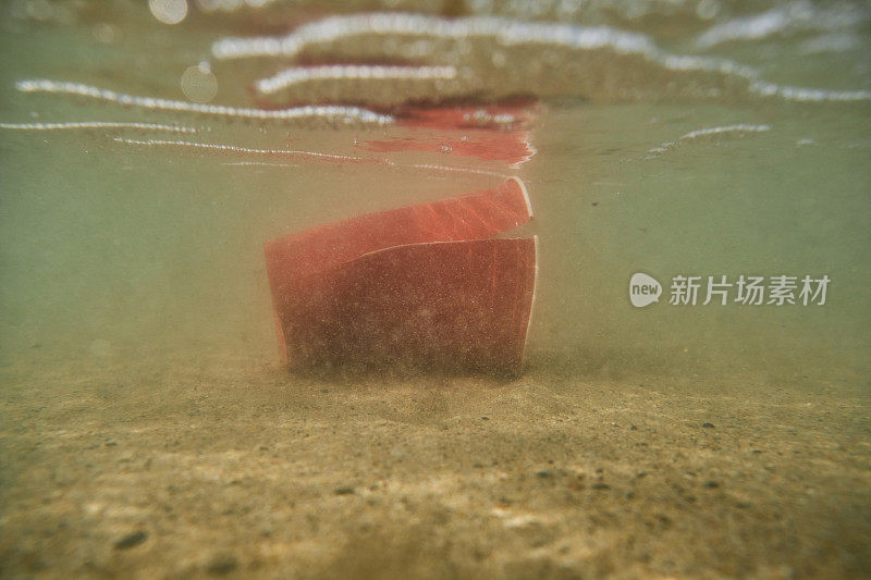 环境问题，废弃的一次性塑料杯在海里。