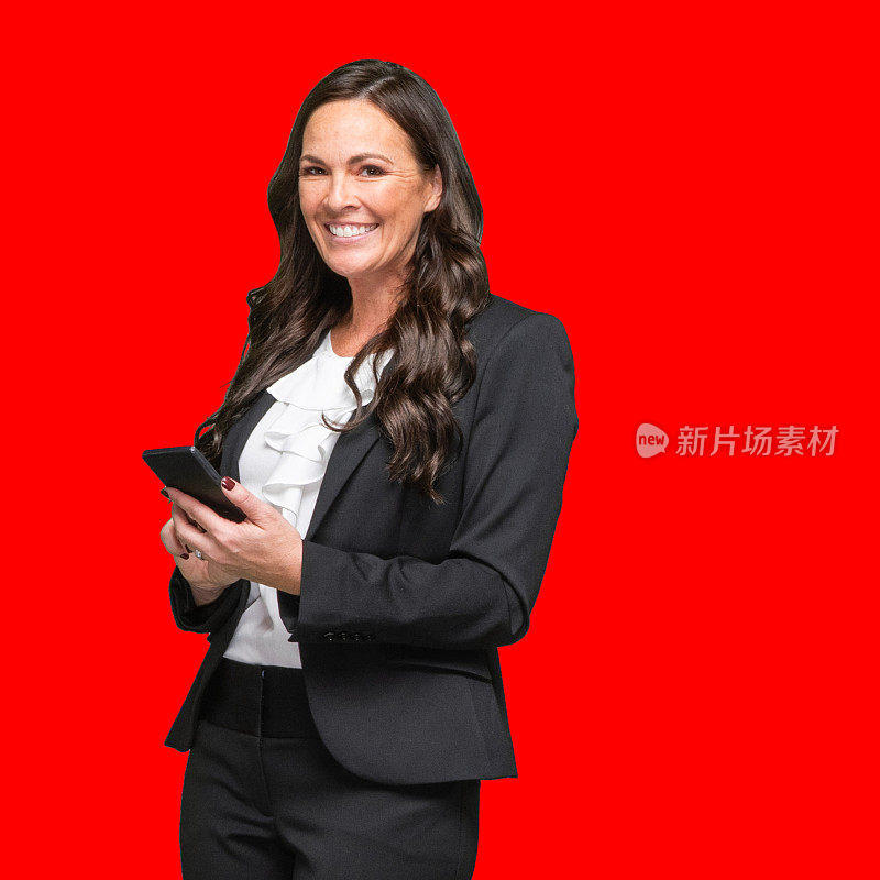 年轻的白人女经理穿着商务装站在有色背景前使用手机