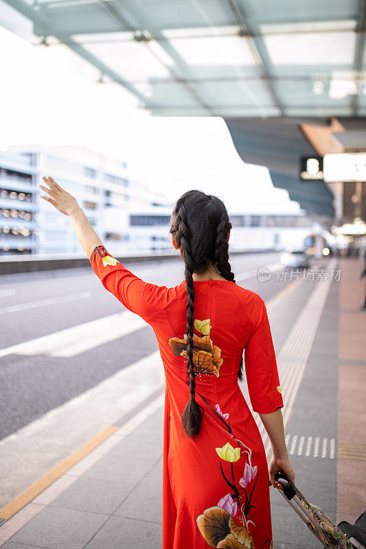 身穿红色奥代的越南女子在机场打出租车