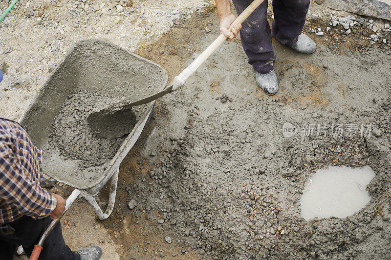 建筑工人在手推车里用铲子搅拌混凝土、水泥和沙子