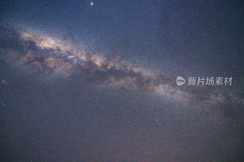 山上有银河和粉红的光。晚上多彩的景观。夏天的星空和山峦。美丽的宇宙。太空背景与星系。旅游的背景