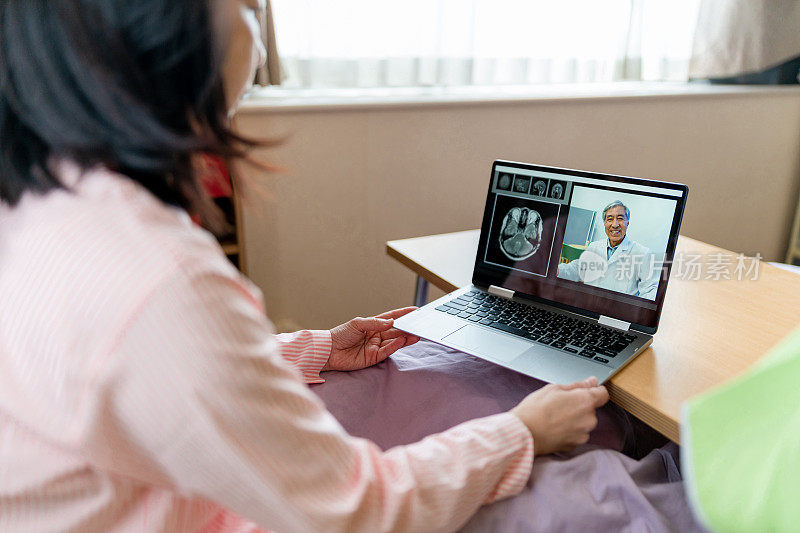 远程健康-妇女视频聊天与医生在家里的笔记本电脑