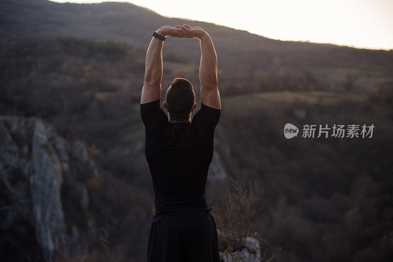 小伙子跑完后在山上伸懒腰