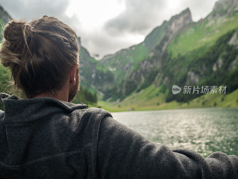 在瑞士，坐在长椅上的男子看着美丽的高山湖泊