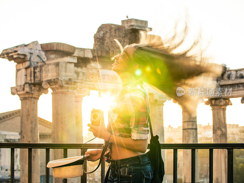 日出时分，在罗马广场，美丽的年轻女子摇晃着金色长发。快乐微笑的游客与古董相机。镜头天赋。罗马,意大利