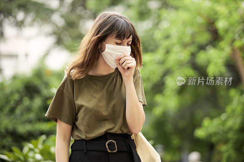 戴防护口罩的妇女在室外咳嗽