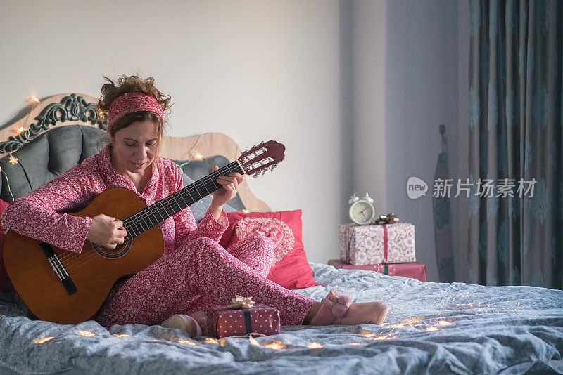 圣诞节的时候，一个女人在床上弹吉他。