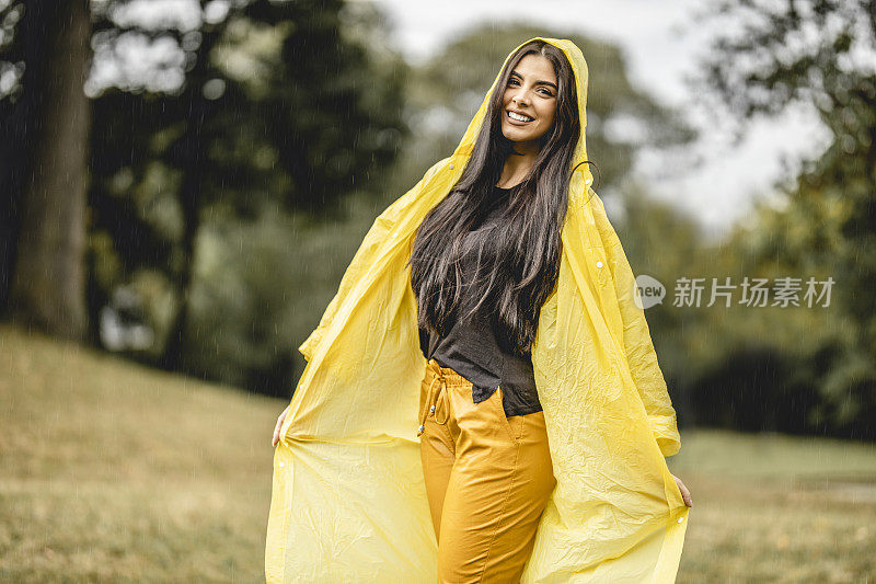 快乐年轻美丽的女人有乐趣，而在雨中跳舞在大自然