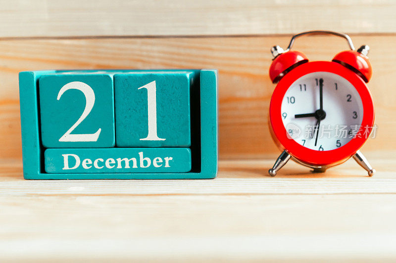 12月21日。蓝色立方体日历，月和日期在木制背景。