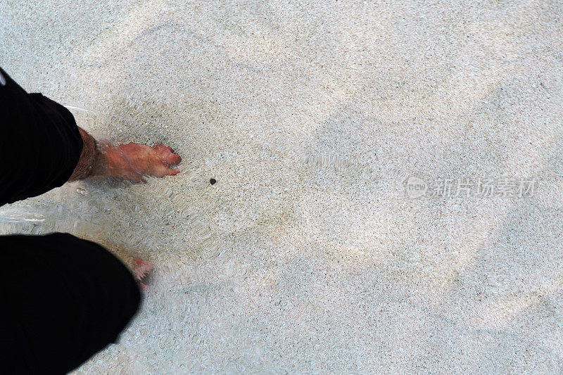 亚洲人的脚在沙滩上散步