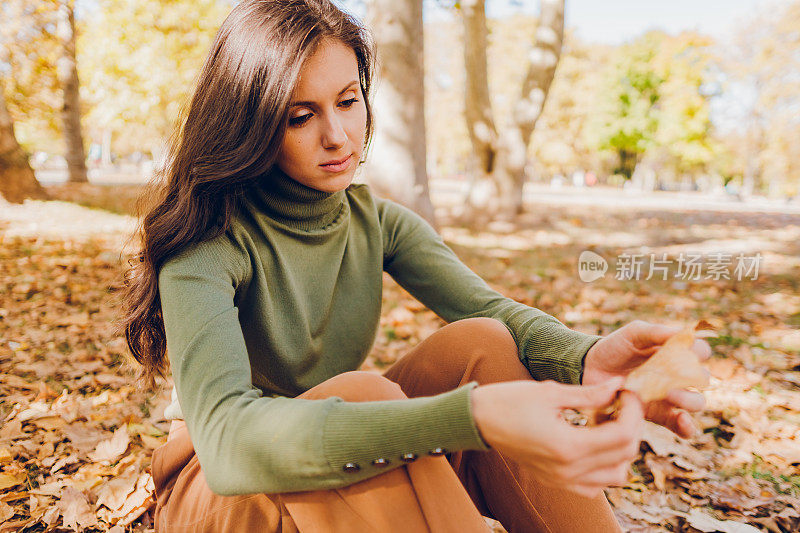秋天的一天，一个悲伤的年轻女子坐在公园里