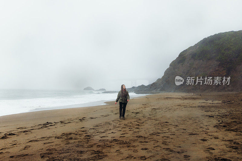 在加利福尼亚旧金山的海滩上散步的女人在思考下雨天