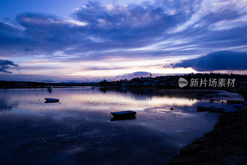 紫色调的蓝色小时与小船漂浮在平静的湖面上