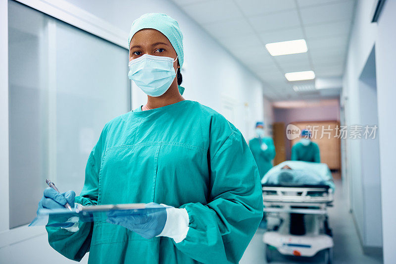 黑人女外科医生在医院给病人做完手术后写病历，看着镜头。