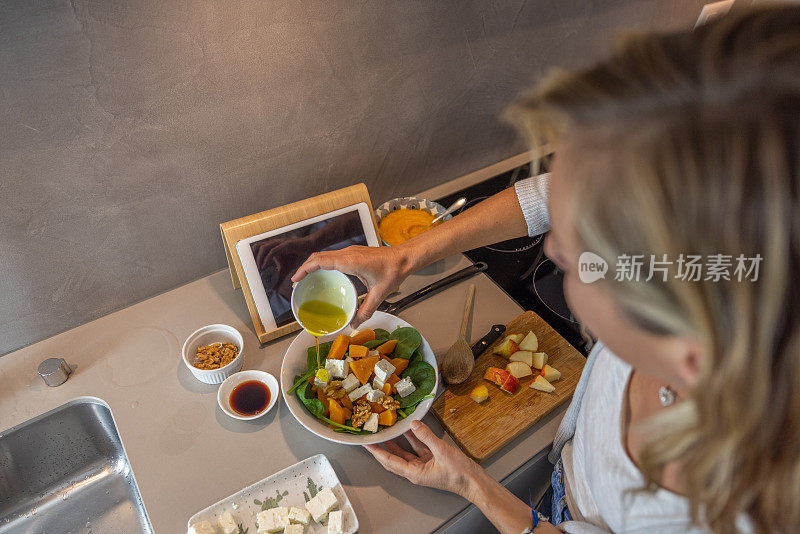 妇女在家里按照数字平板电脑上的食谱准备健康食品