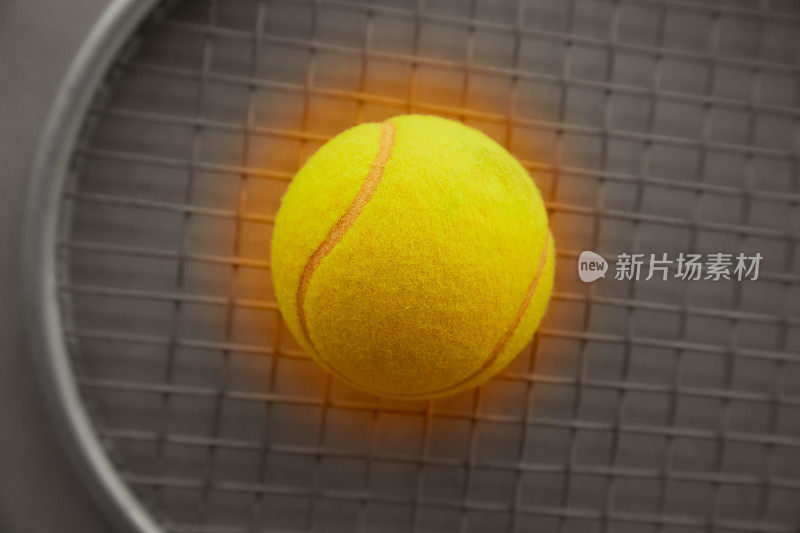 一个明黄色的网球，背景是一个网球拍，正在打网球，属性为大网球