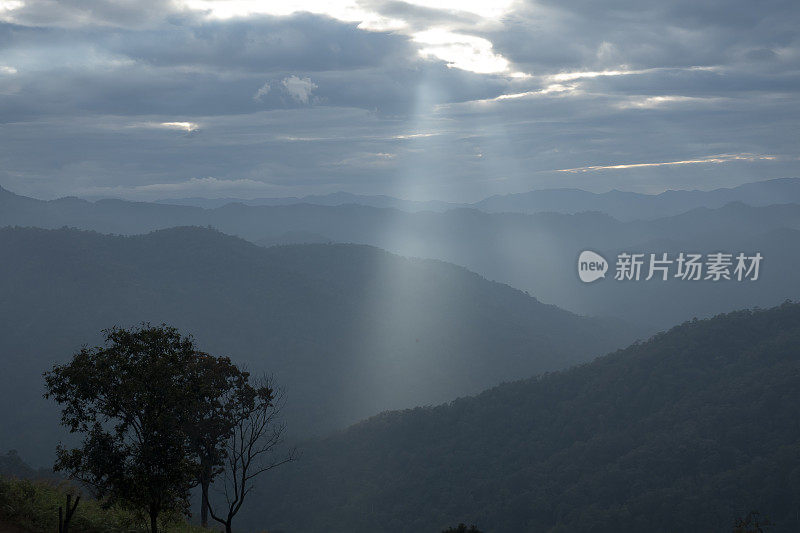 太阳光线透过云层在山谷的山丘上被穿透云层的太阳光线照亮