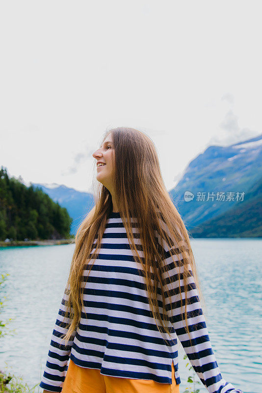 快乐的女旅行者的肖像在山湖边沉思夏天的户外