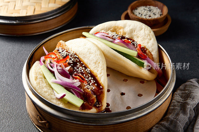 正宗的亚洲菜:包馍配鸭和蔬菜，放在黑色的桌子上蒸锅里