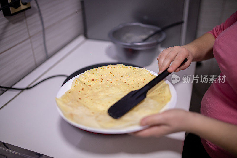 女人用锅铲在电煎锅上翻转煎饼