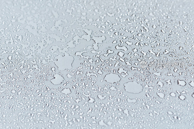 水滴凝结在透明玻璃的白色背景纹理上。背景玻璃上覆盖着抽象的水滴。有选择性的重点。