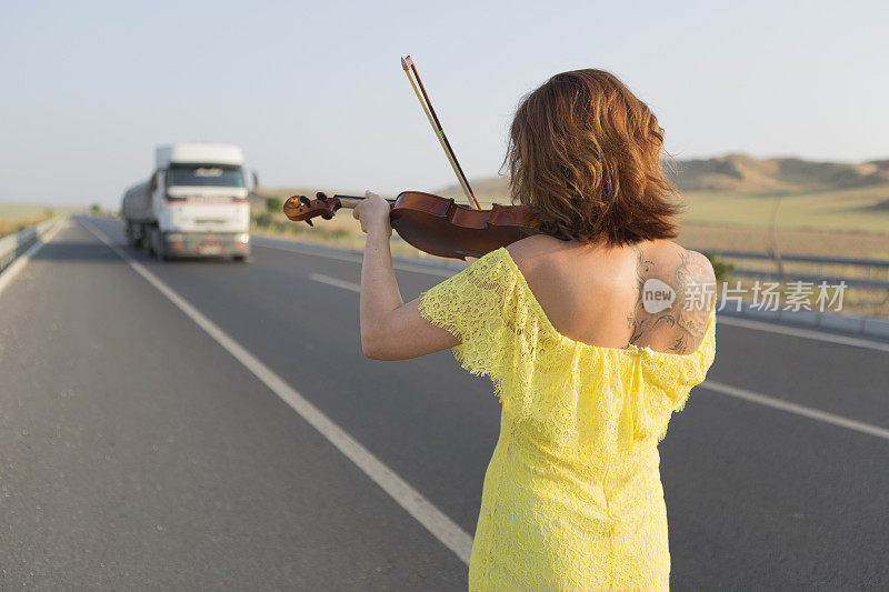 在高速公路上为车辆拉小提琴的女人