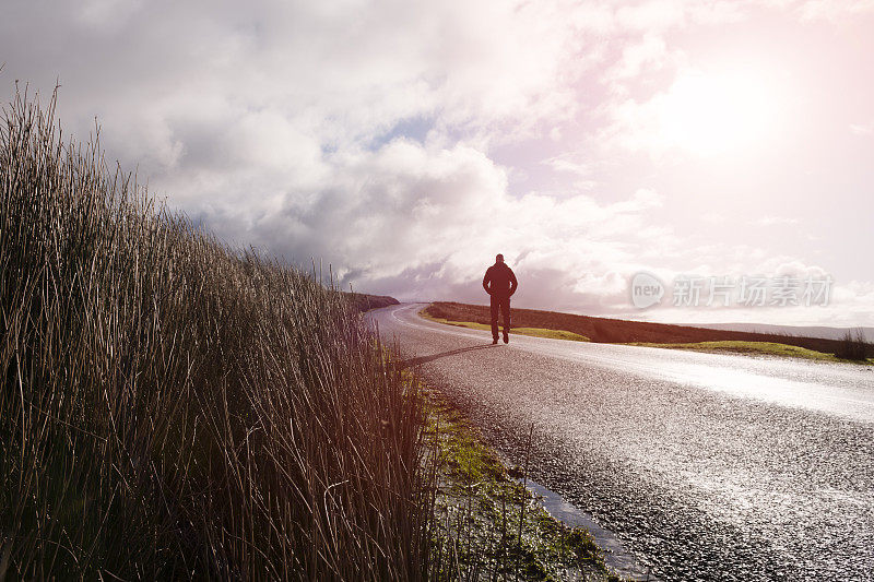 一个人走在开阔的乡村道路上