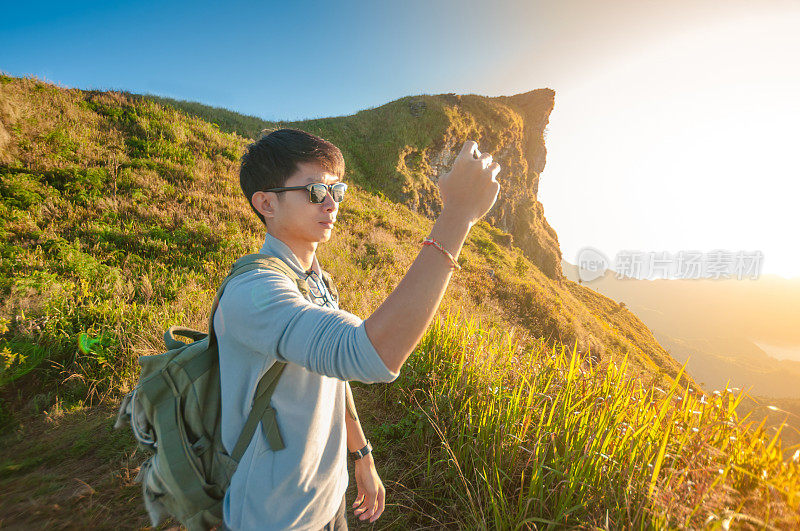 年轻的旅行者站在山上望着夕阳。