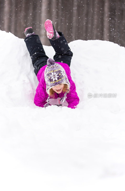 女孩在冬天从雪堆上滑下来