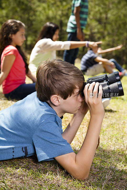 青少年:公园里的观众。一个用望远镜看，另一个指着。