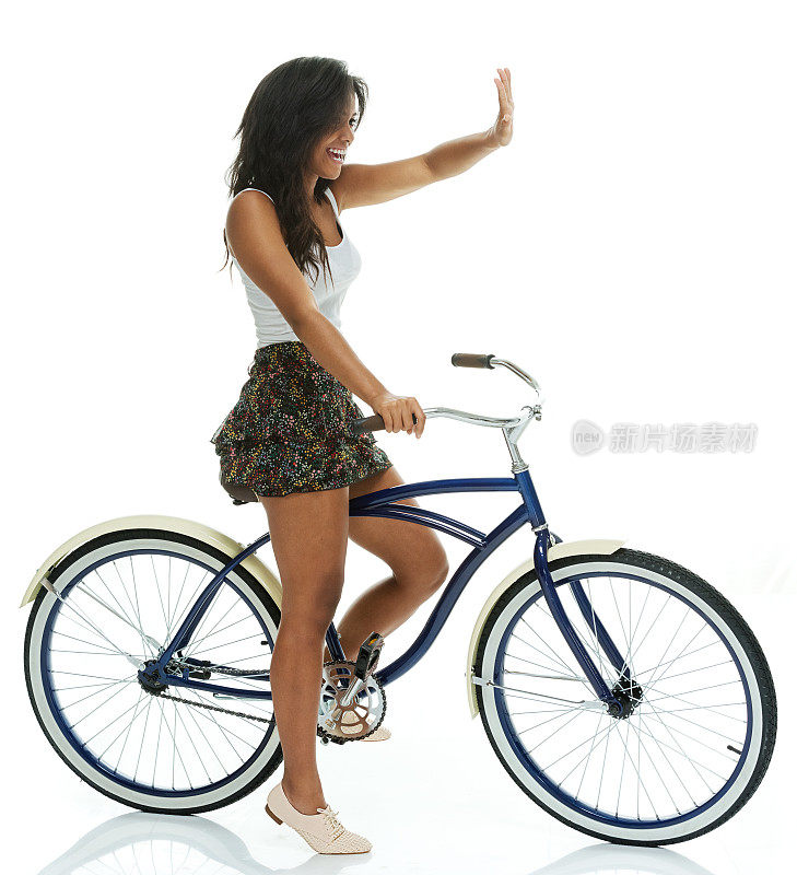 欢快的女性骑着自行车，挥手致意