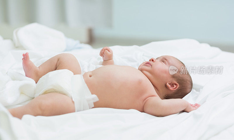 刚出生的婴儿裹着尿布躺在床上