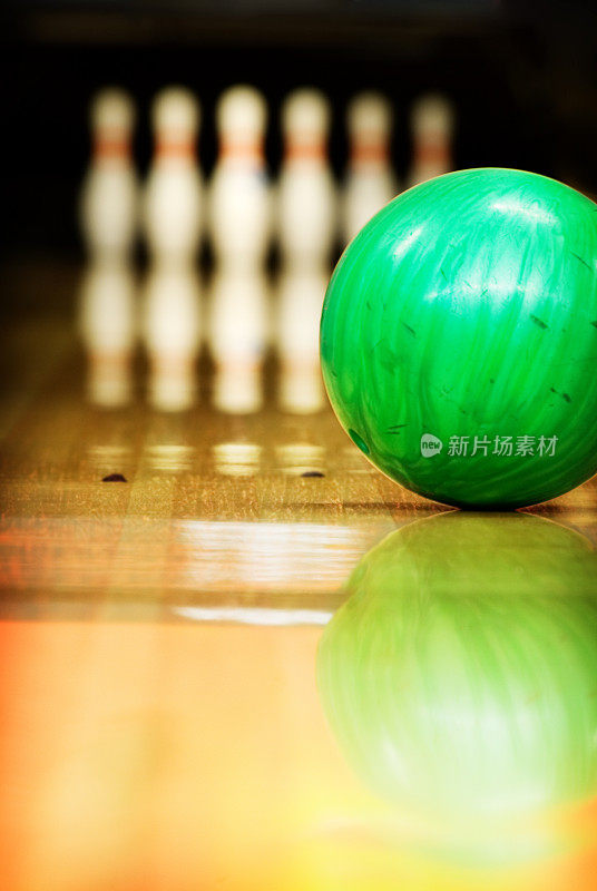 一个绿色的保龄球沿着球道向10个瓶子靠近