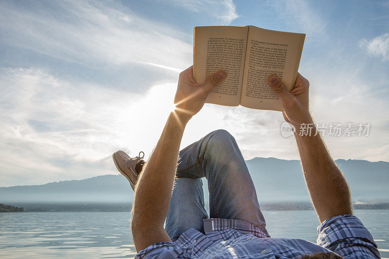 年轻人躺在防波堤上，读着一本书