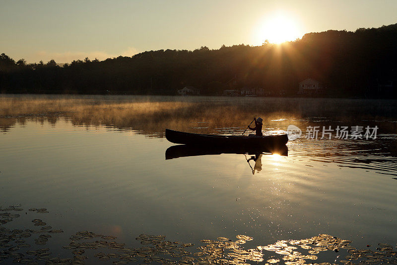 户外女孩在湖上划着独木舟背光的日出