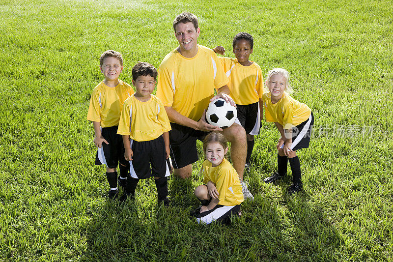 教练与不同的团队的孩子踢足球