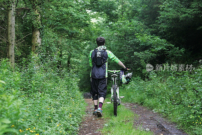 山地车在森林小径推自行车的后视图
