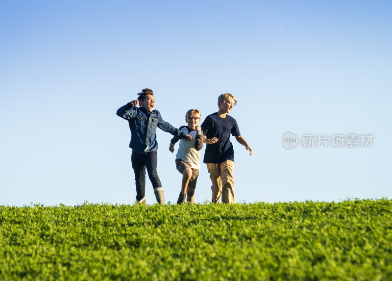 三个男孩在小山上跑步。