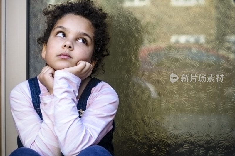 人物:不快乐的孩子(7-8岁)，手放在下巴坐在外面