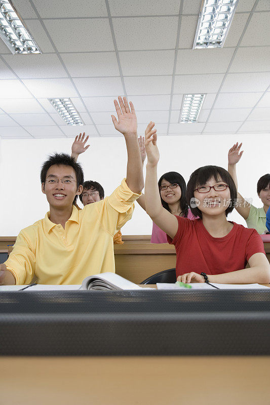 大学生在教室里举手，微笑