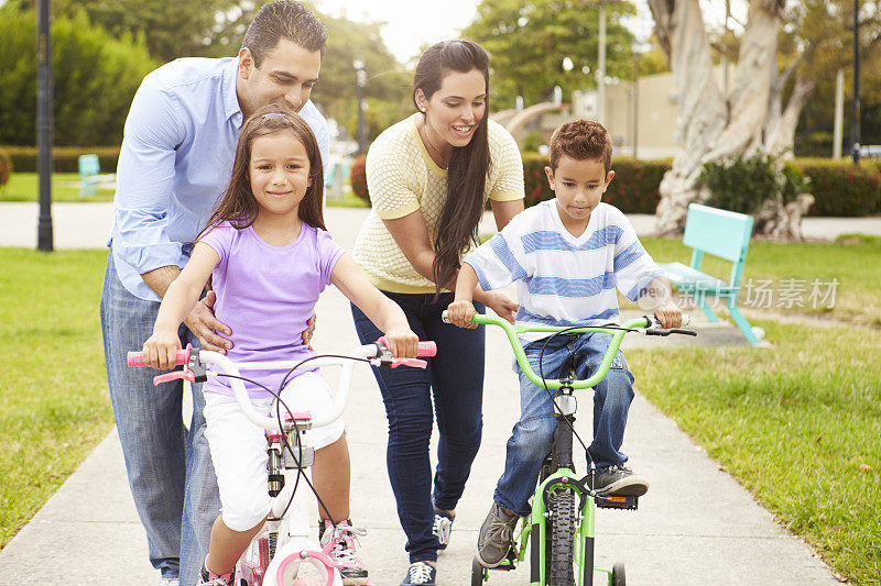 父母教孩子在公园里骑自行车