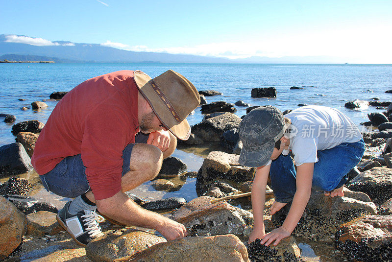 男人和孩子岩石池，海滩景色，冬天