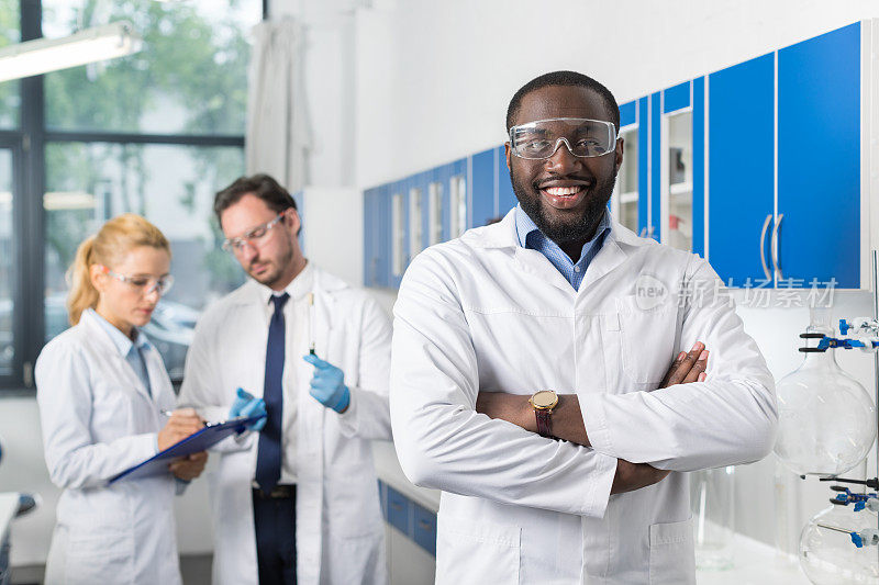 笑容灿烂的非裔美国科学家站在实验室同事面前记录实验或研究结果