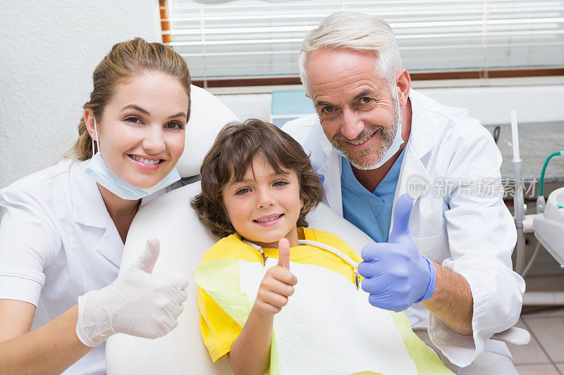 儿科牙医助理和小男孩都对着镜头微笑，竖起大拇指