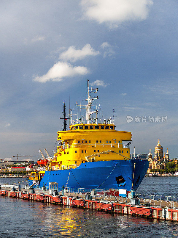 一艘黄蓝色的破冰船停在靠近圣彼得堡市堤岸的码头上