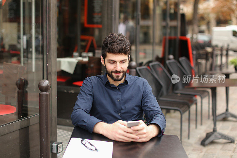 坐在咖啡桌旁用智能手机聊天的快乐男人