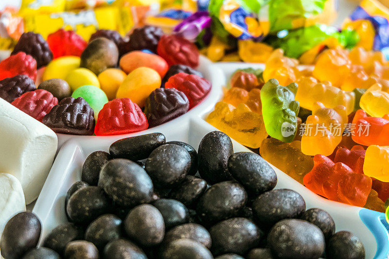一套放在托盘里的松散的糖果。一堆堆的巧克力糖花生，果酱熊和浆果，棉花糖。视野深度有限的透视视图。